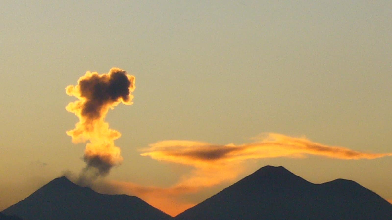 An ash and ember column rising from Volcán de Fuego at dusk, photographed from the Acatenango ridge