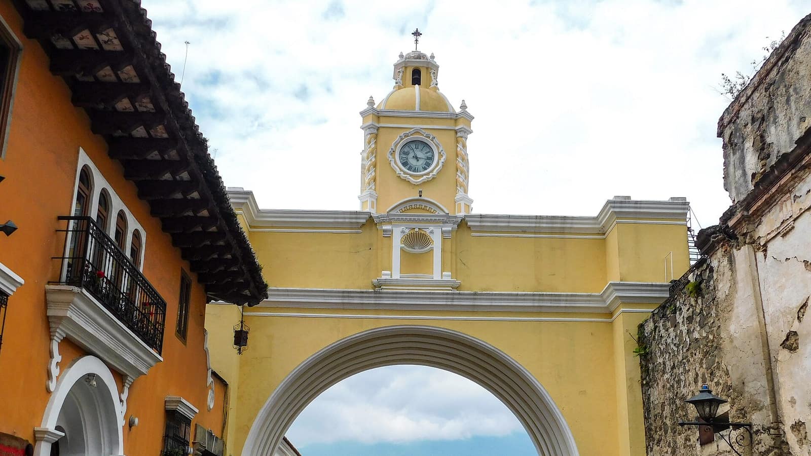 The yellow Santa Catalina arch spanning a cobbled street in Antigua Guatemala, with its clock tower above